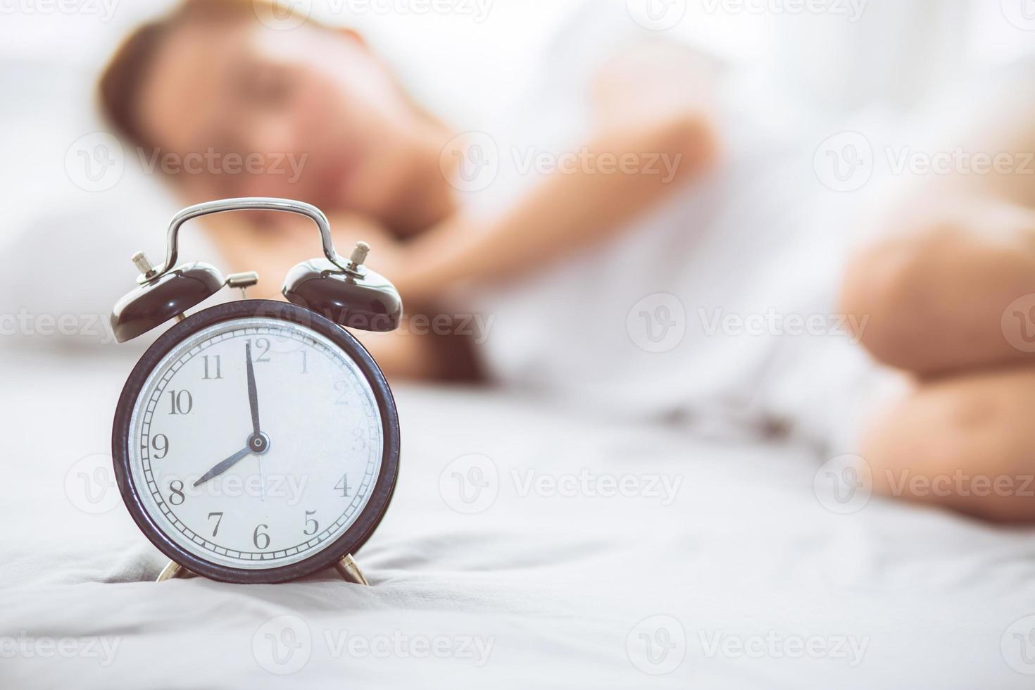 Young asian woman turn off alarm clock in good morning. photo