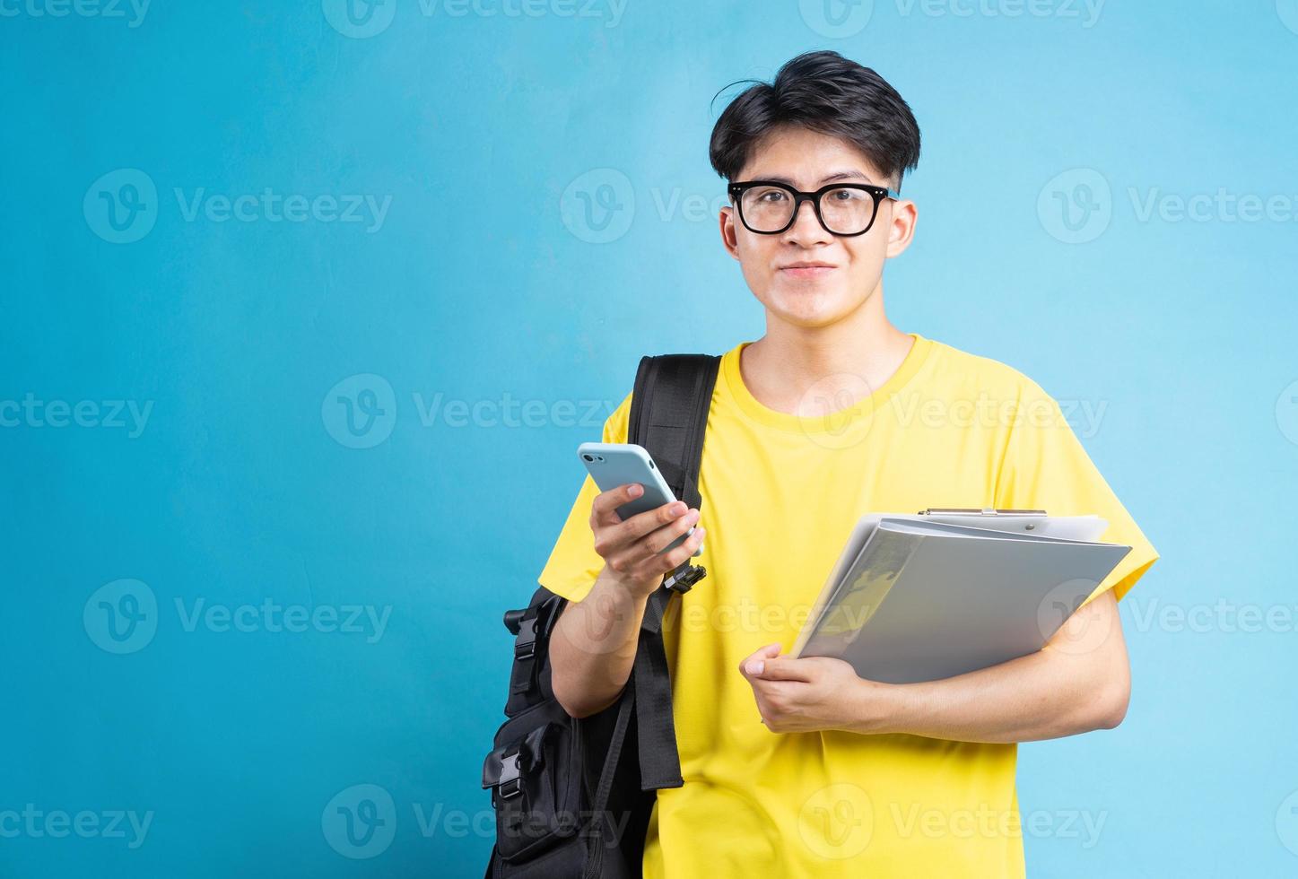 Asian male student portrait, isolated on blue background photo