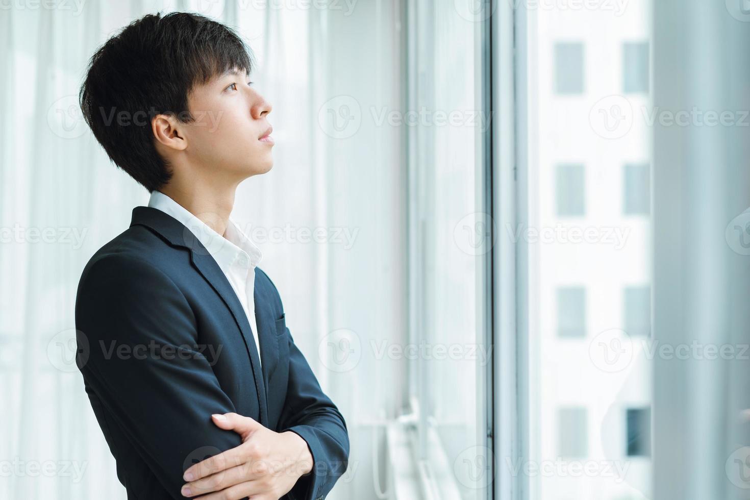 A man in a business suit looks out the window photo