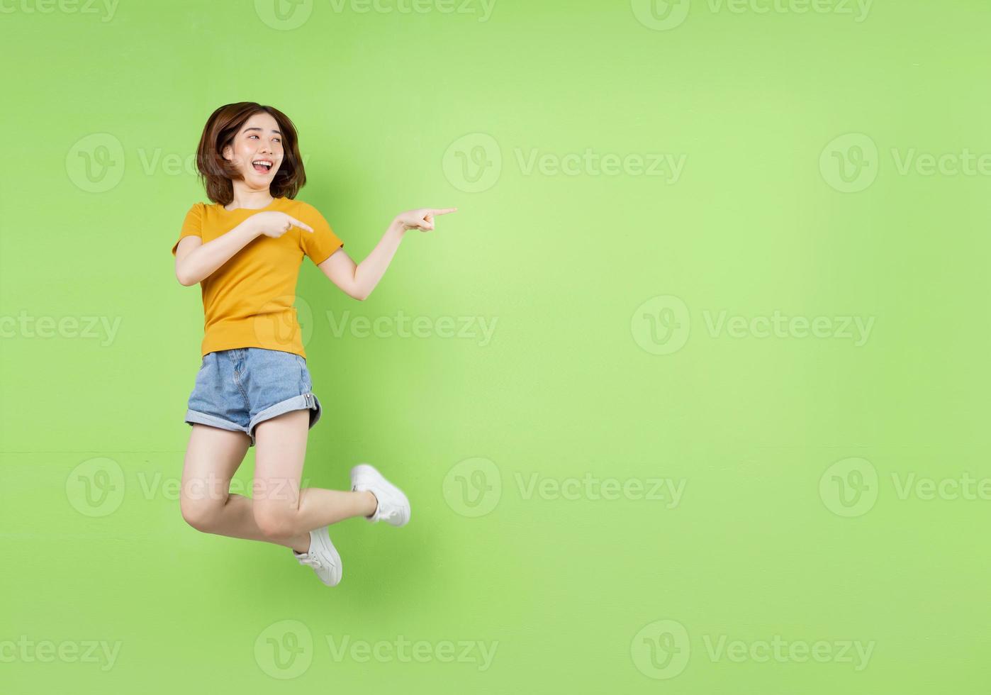 joven asiática saltando sobre un fondo verde foto