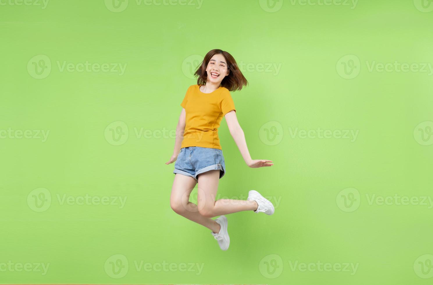 Young Asian girl jumping on a green background photo