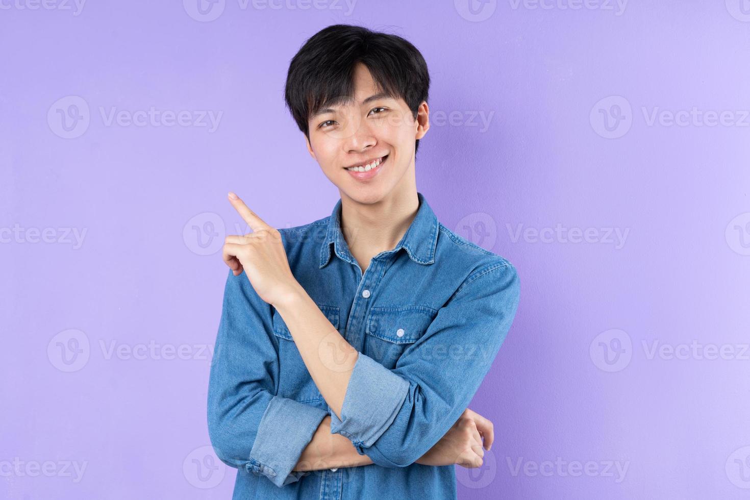 Portrait of Asian man in blue shirt posing on purple background photo