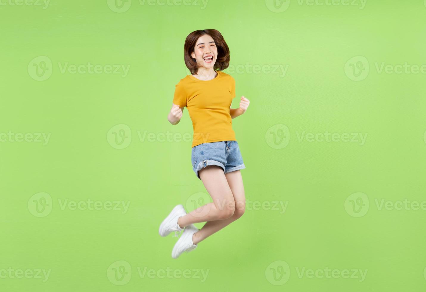 Young Asian girl jumping on a green background photo