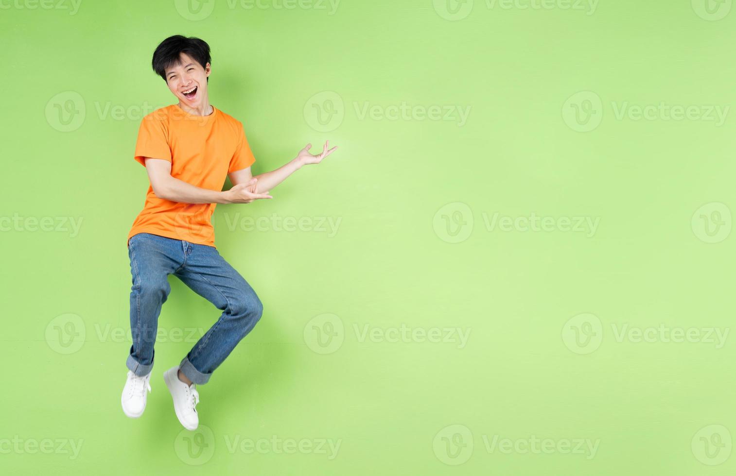 young asian man jumping , isolated on green background photo