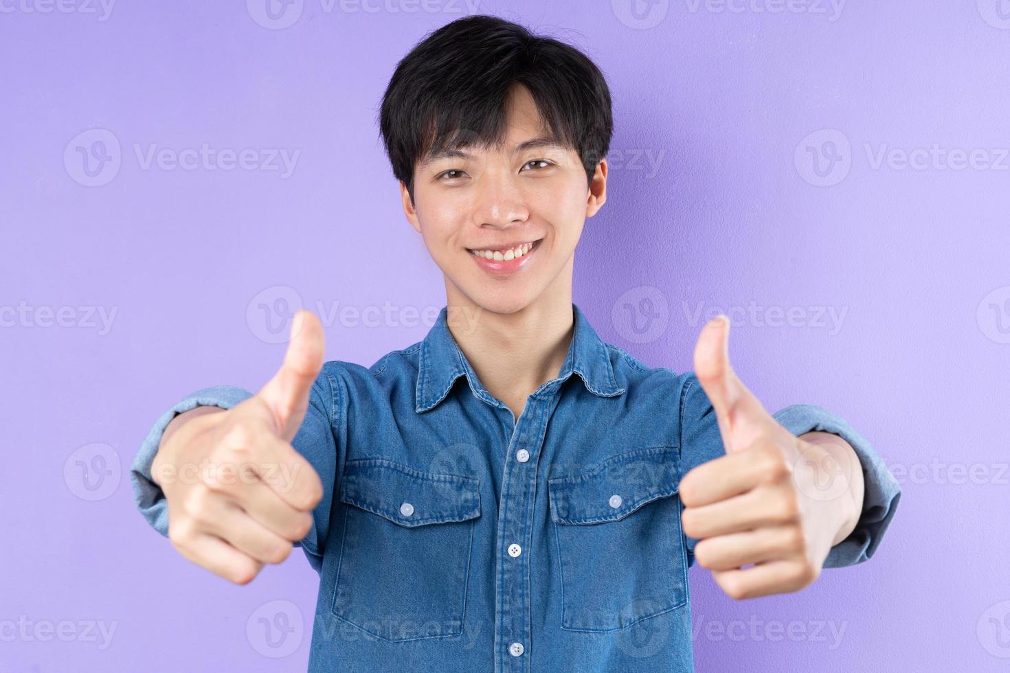 retrato, de, hombre asiático, en, camisa azul, posar, en, fondo púrpura foto