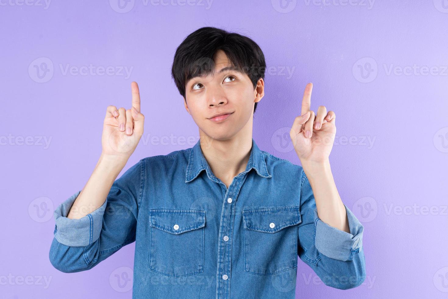 Portrait of Asian man in blue shirt posing on purple background photo