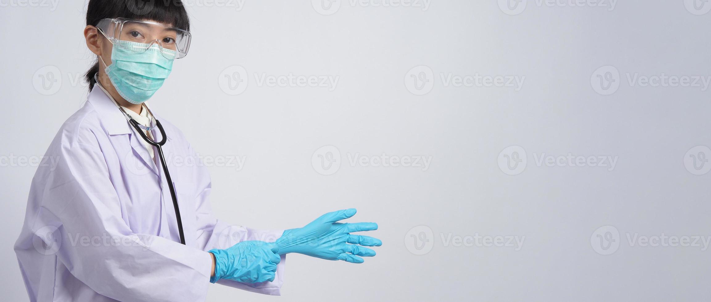 usando guantes. El médico asiático usa guantes de manos de nitrilo de goma azul. foto