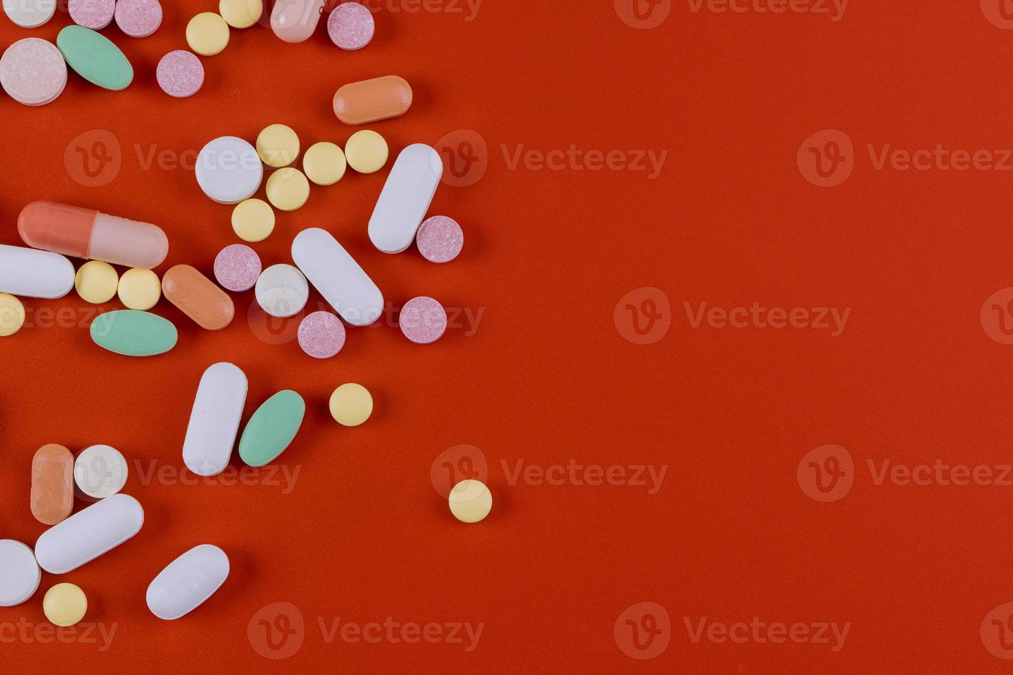 Group of assorted tablets pills capsules on red background. photo