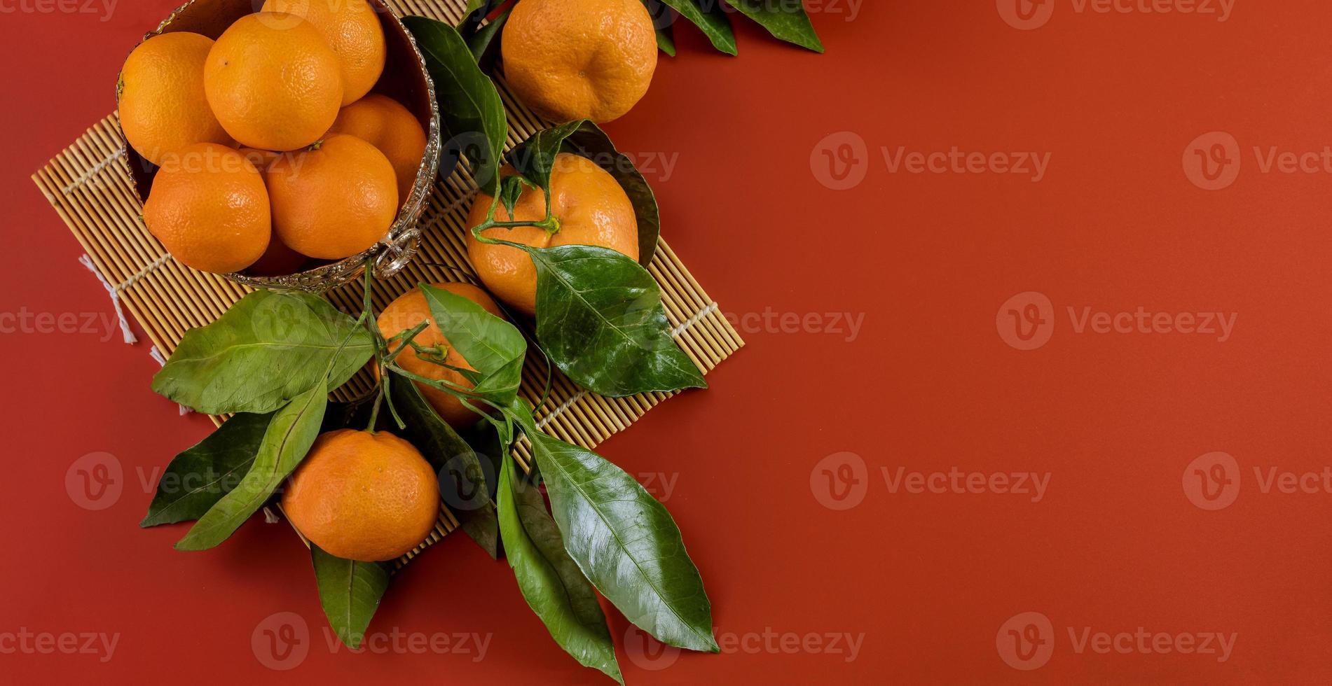 Ripe bright raw tangerines on branch with green leaves in a bowl photo