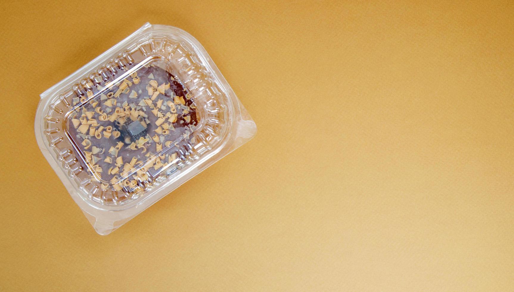 Chocolate donut in a plastic container on a brown or coffee background photo