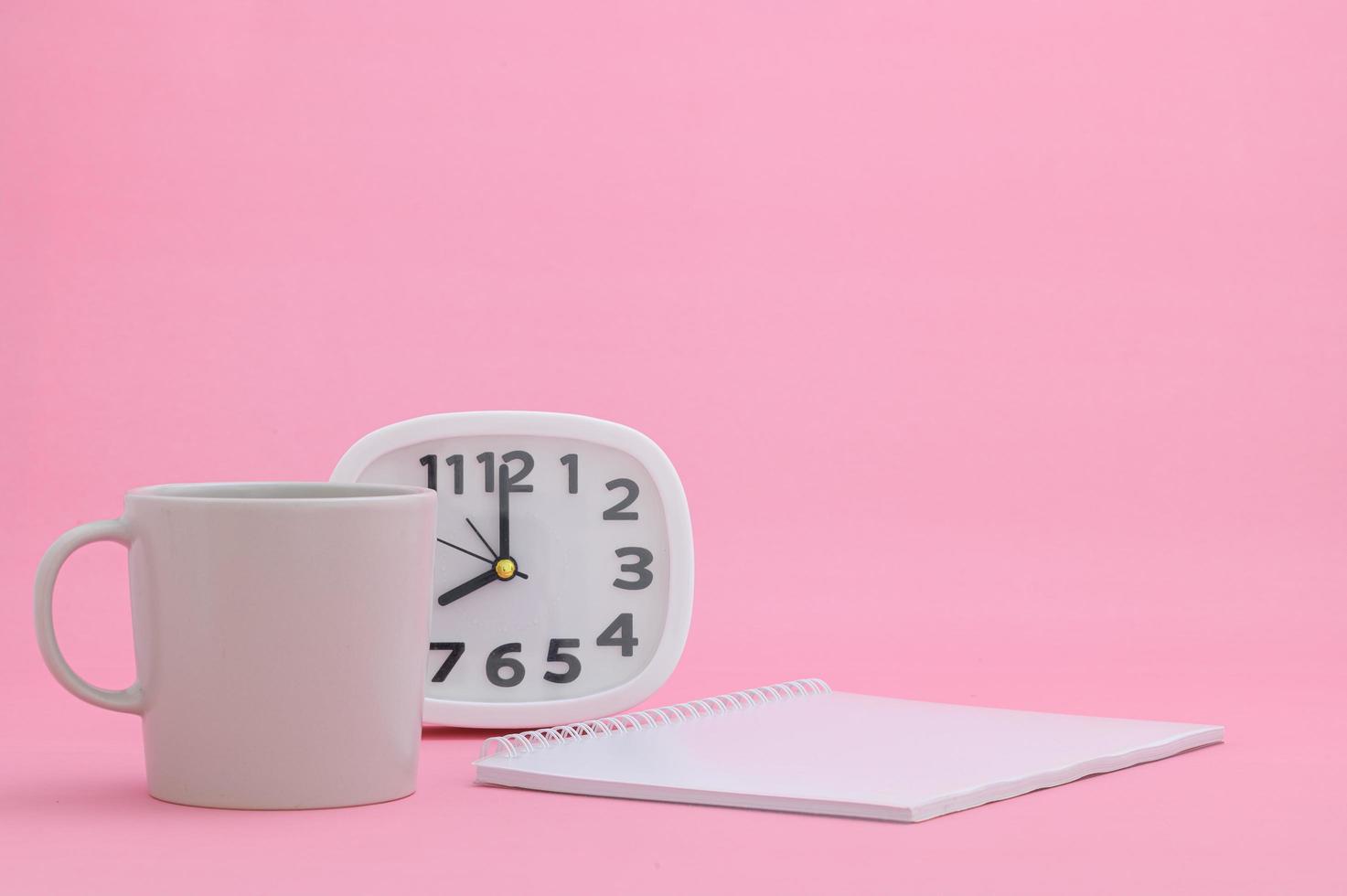 Notepad and cup on pink background photo