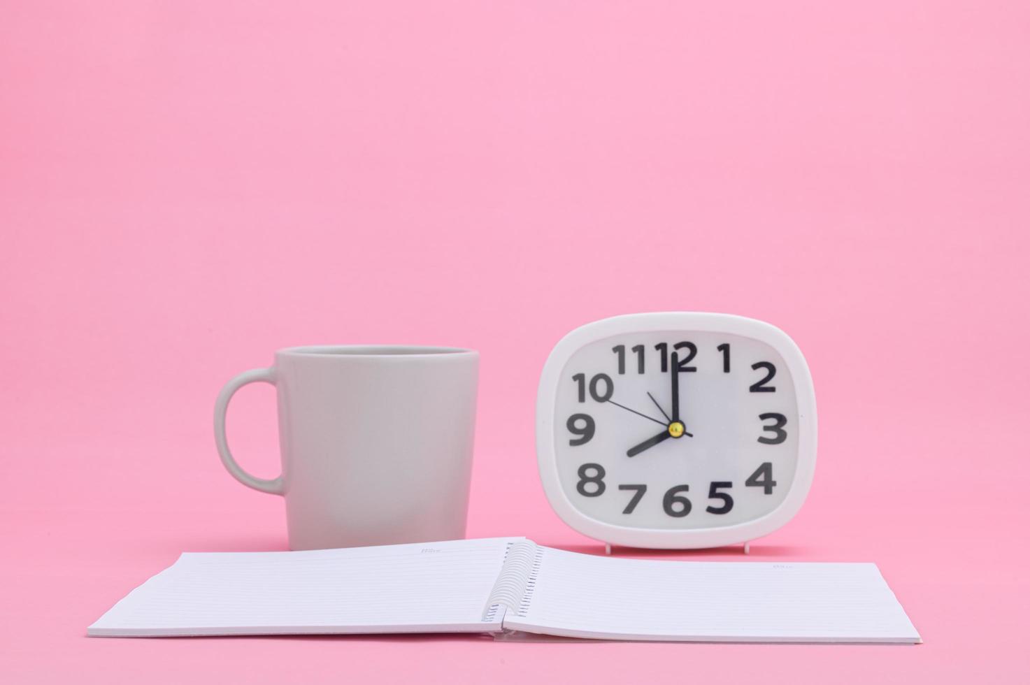 Notepad and cup on pink background photo