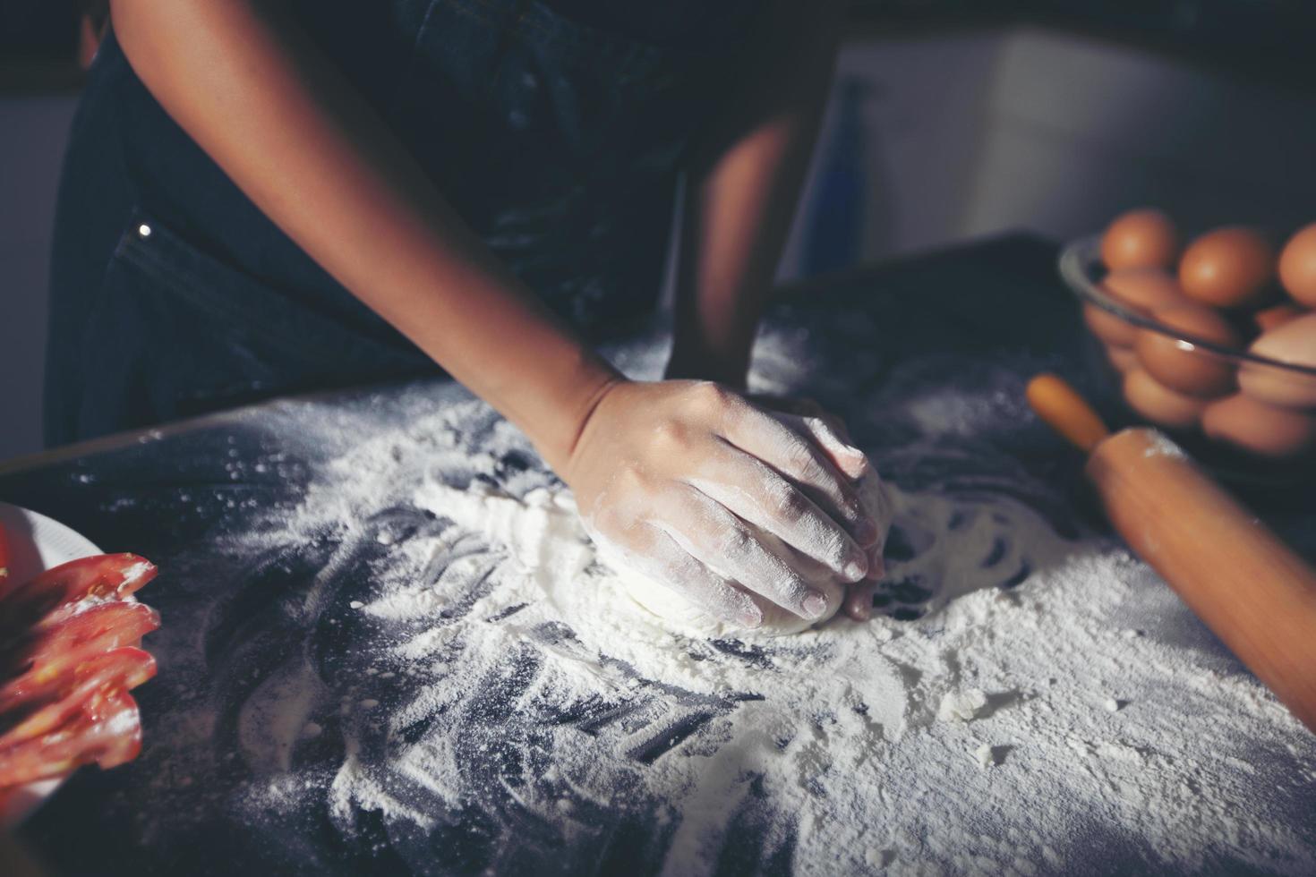 Las mujeres asiáticas preparando una pizza, en la mesa de la cocina foto