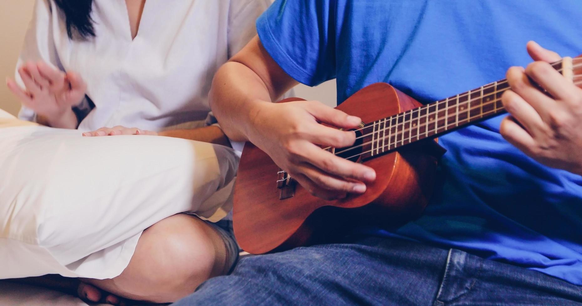 pareja tocando el ukelele en la cama foto