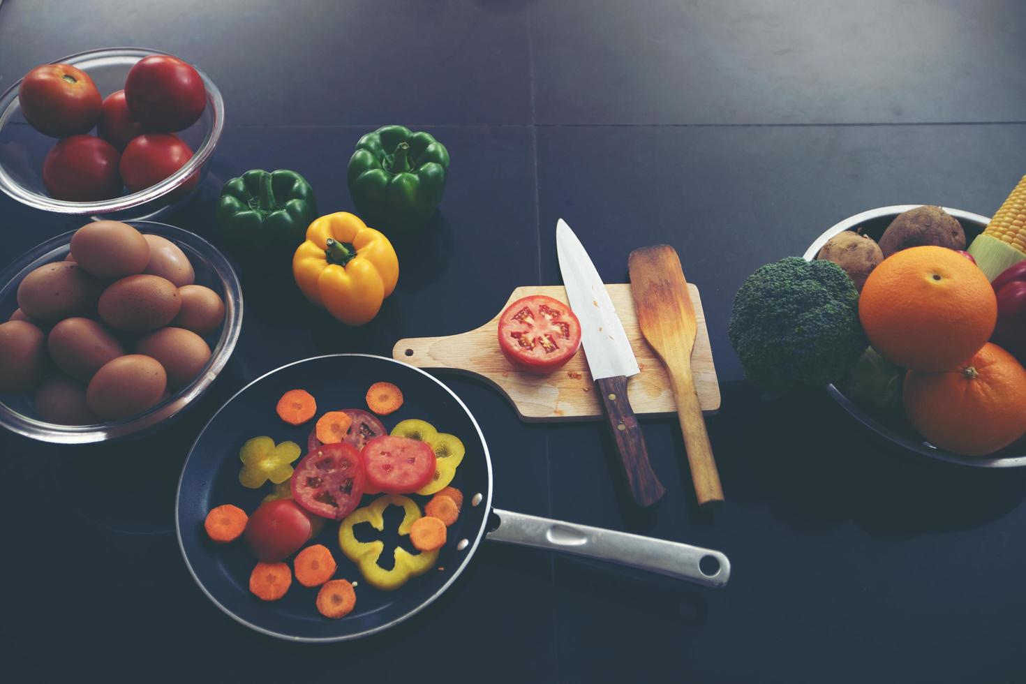 Food and fresh vegetables and salad bowls on kitchen table photo