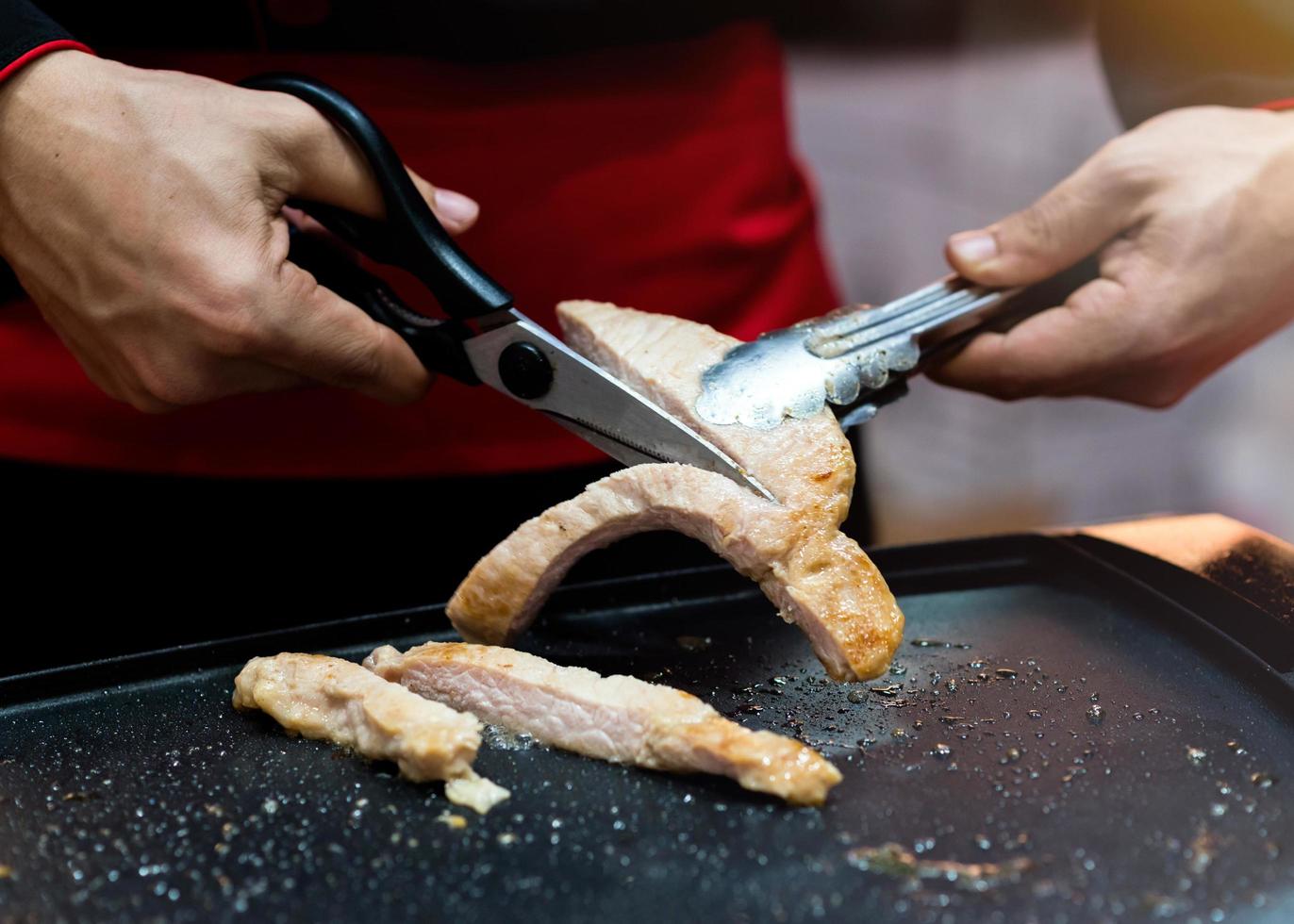 Hand hold scissors cutting  grilled pork steak photo