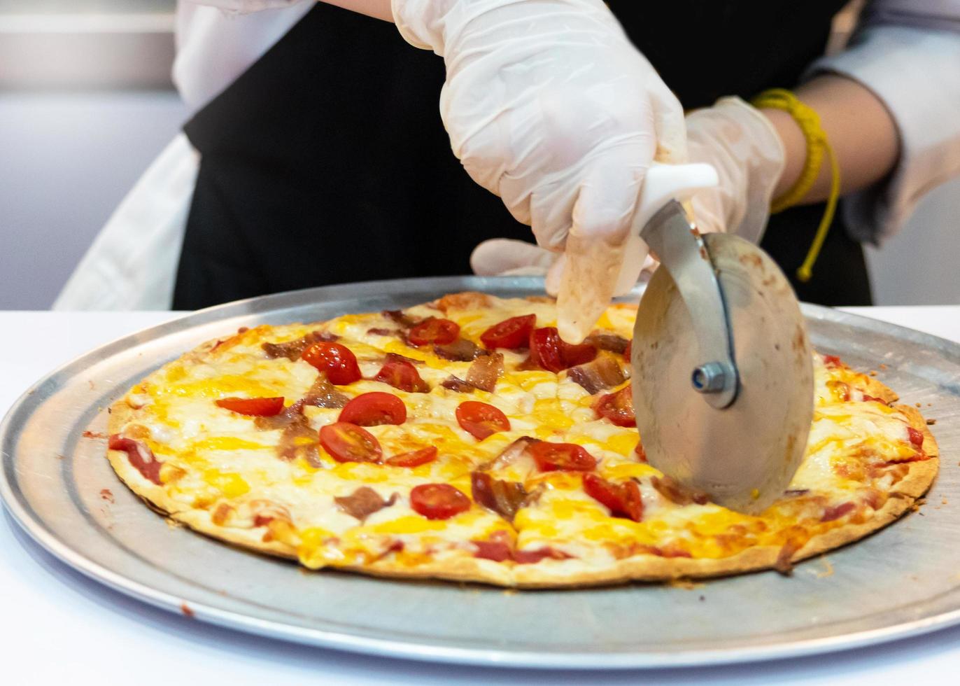 Primer plano de la mano del chef cortando pizza en la cocina foto