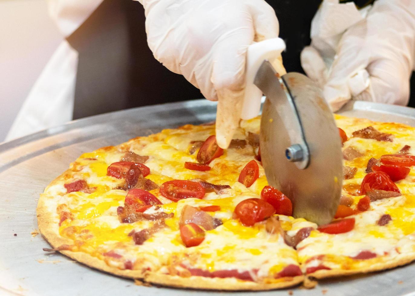 Closeup hand of chef cutting pizza in kitchen photo