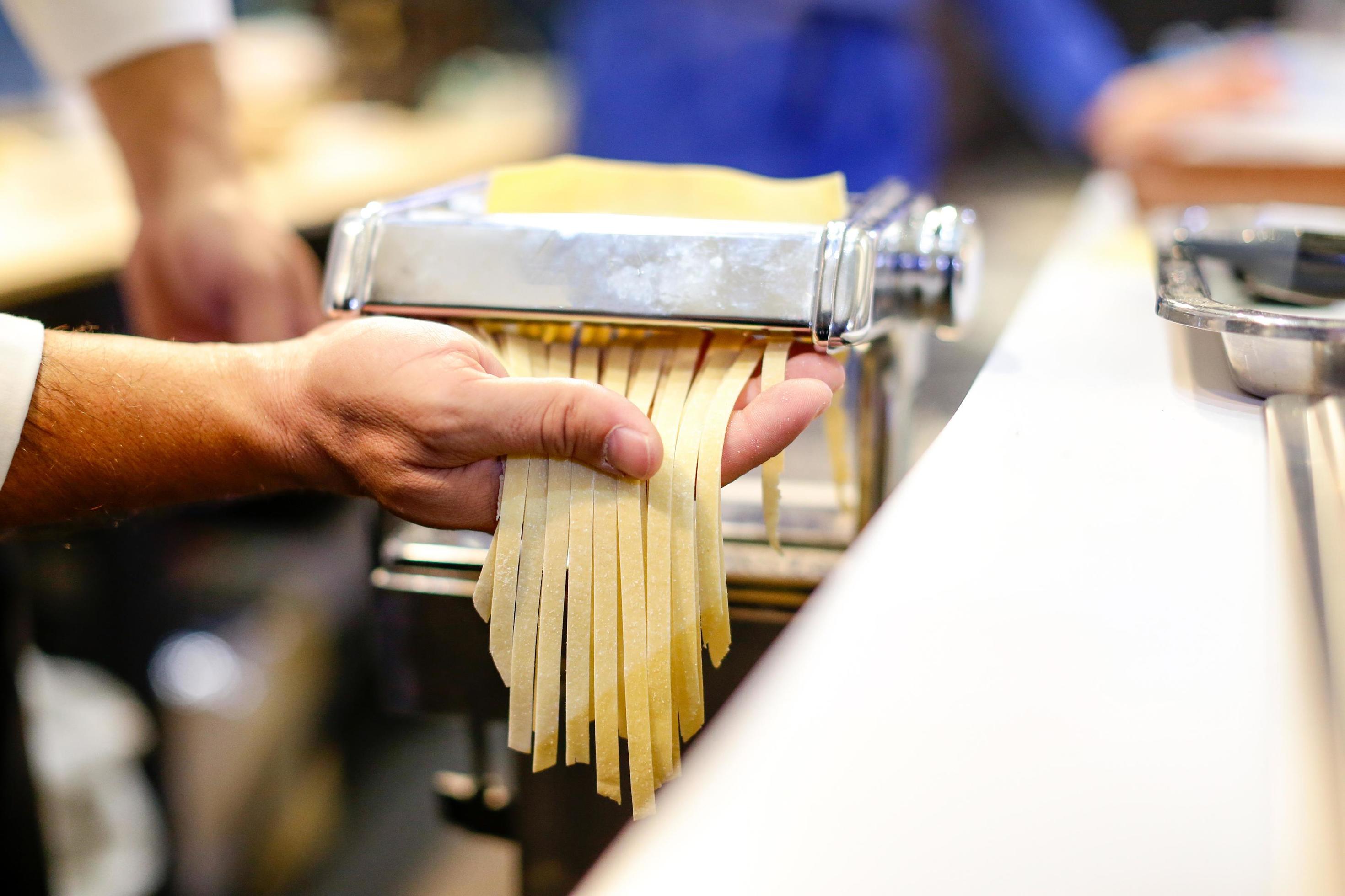 Chef rodando la masa con una máquina de pasta. máquina para hacer