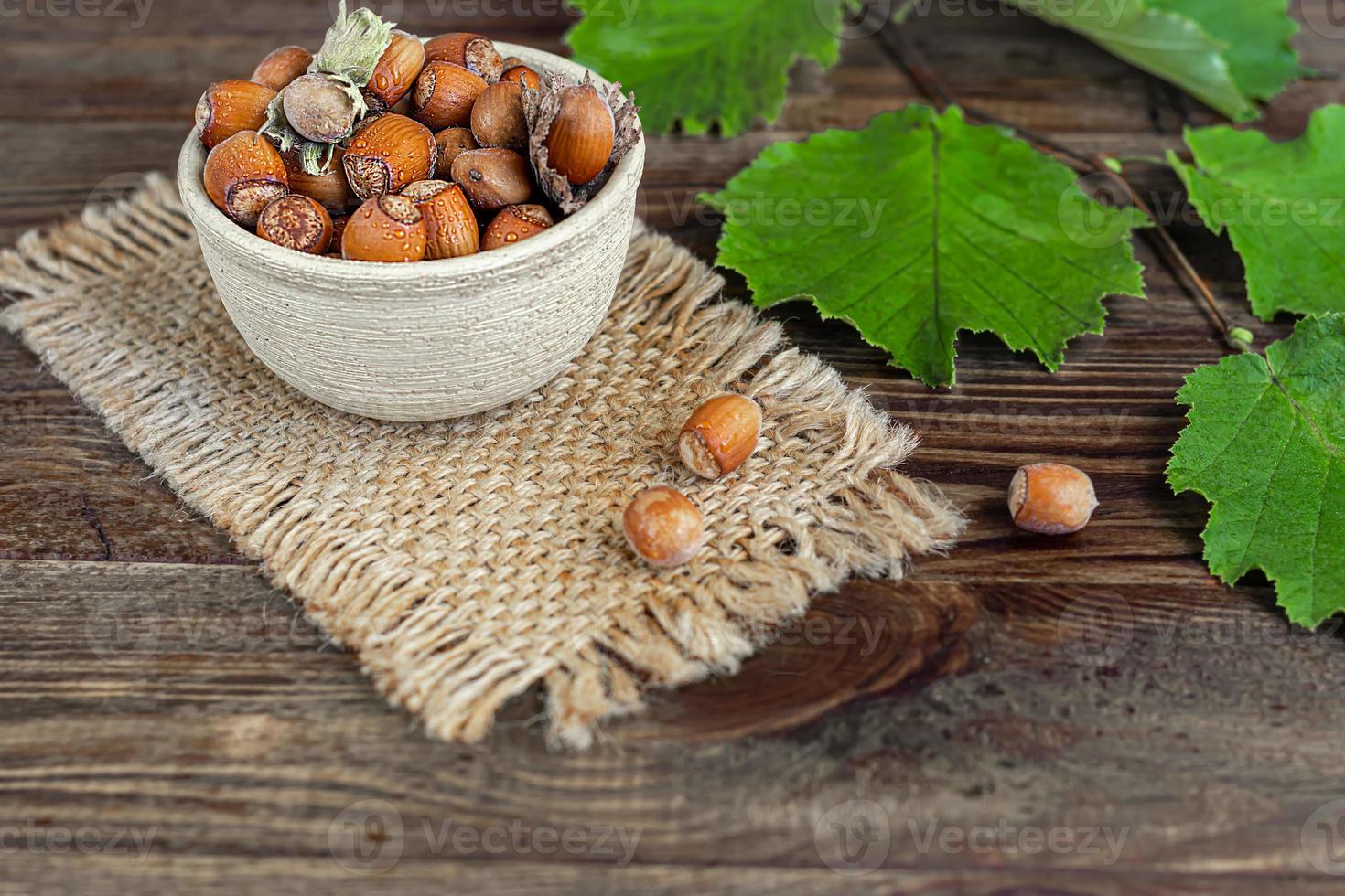 Hazelnuts on a wooden background with green leaves. photo