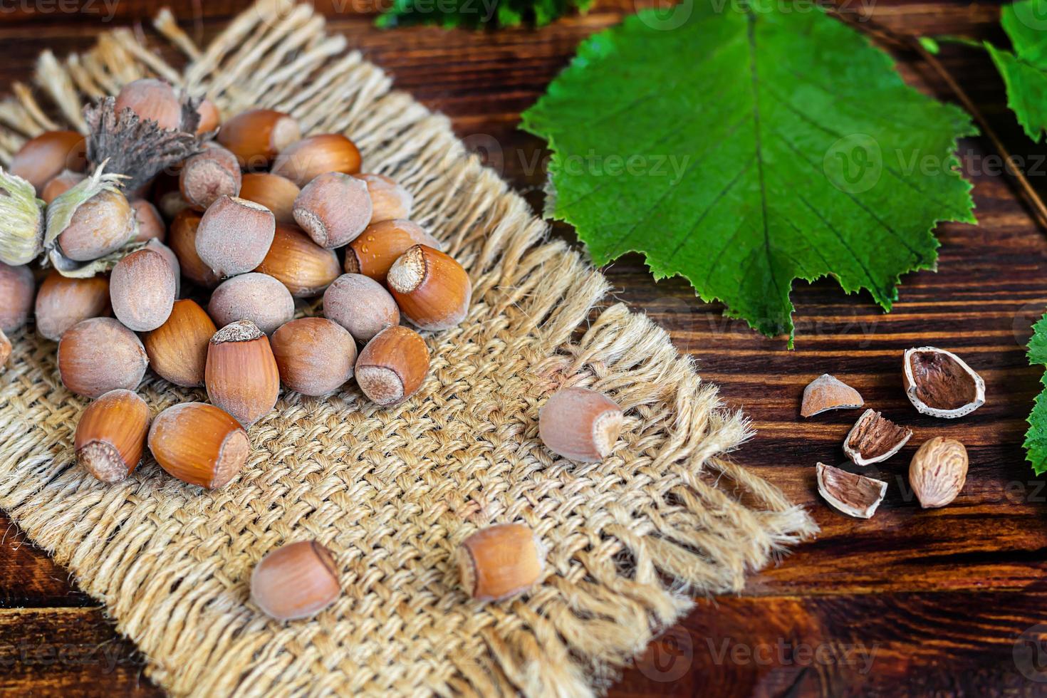 Hazelnuts on a wooden background with green leaves. photo