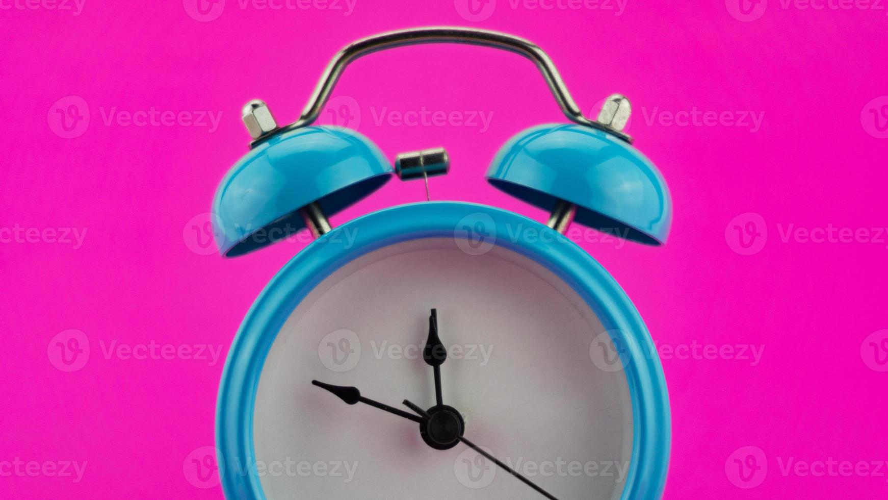 Blue alarm clock on pink background photo