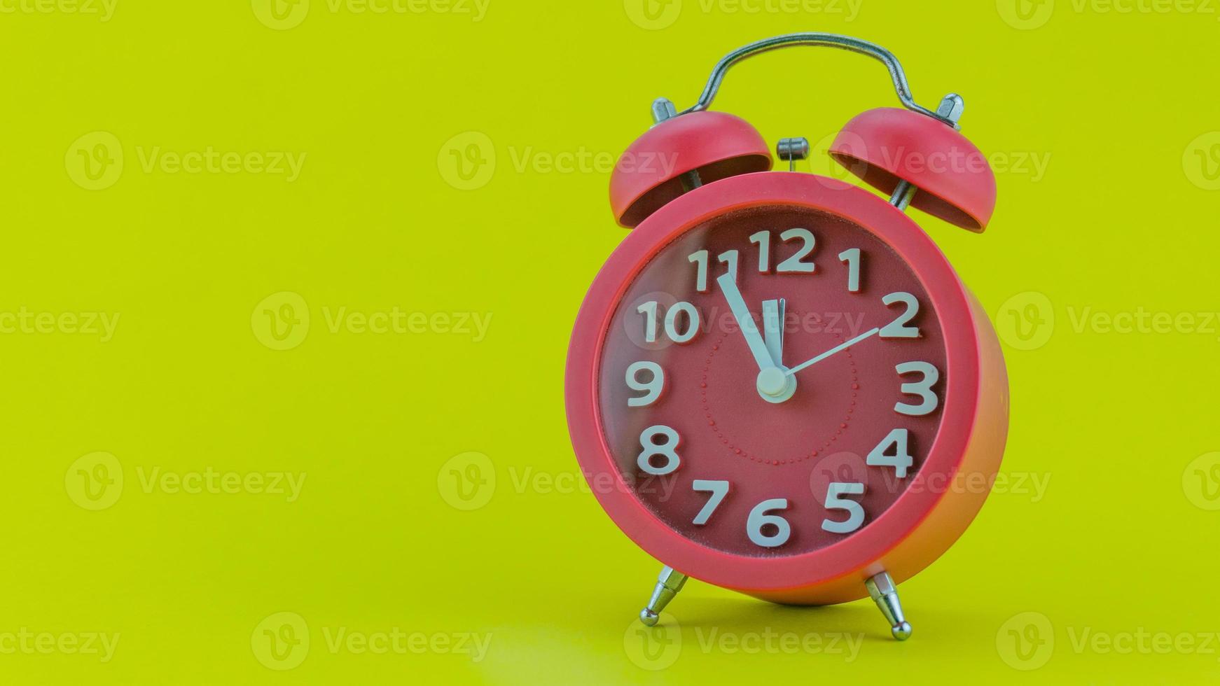 Red alarm clock on yellow background photo