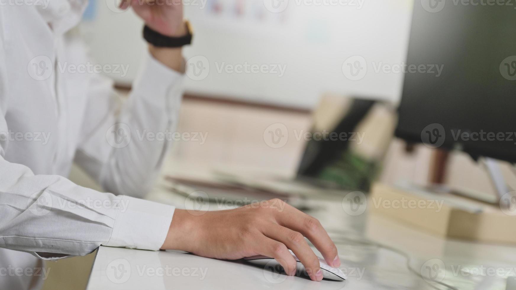 mano del programador usando el ratón de la computadora, computadora en el escritorio del programador. foto