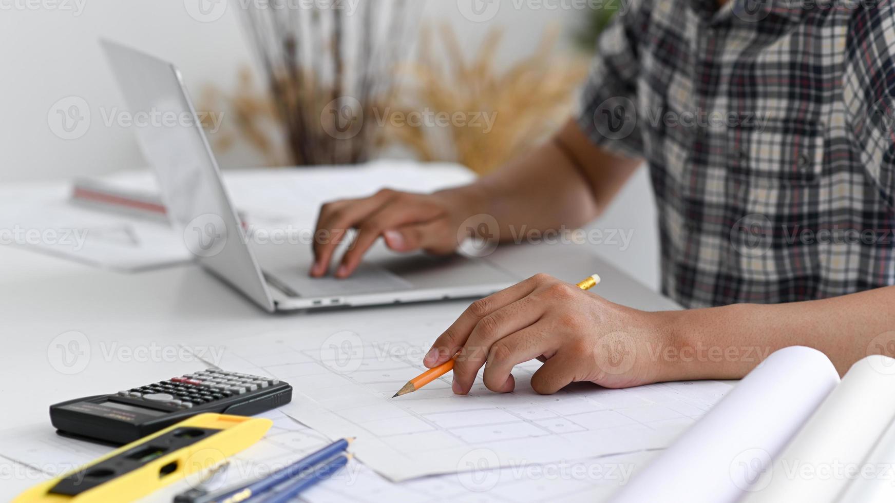 El hombre usa un lápiz para escribir en el plano de la casa. foto