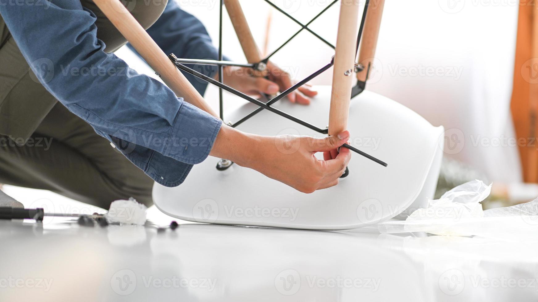 un joven reparando una silla moderna, silla de bricolaje. foto