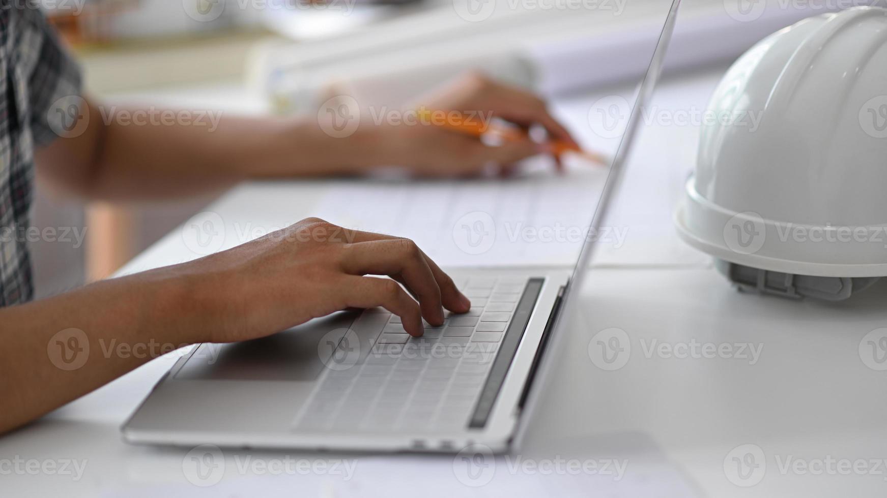 La mano del hombre joven está utilizando un teclado de computadora portátil. foto