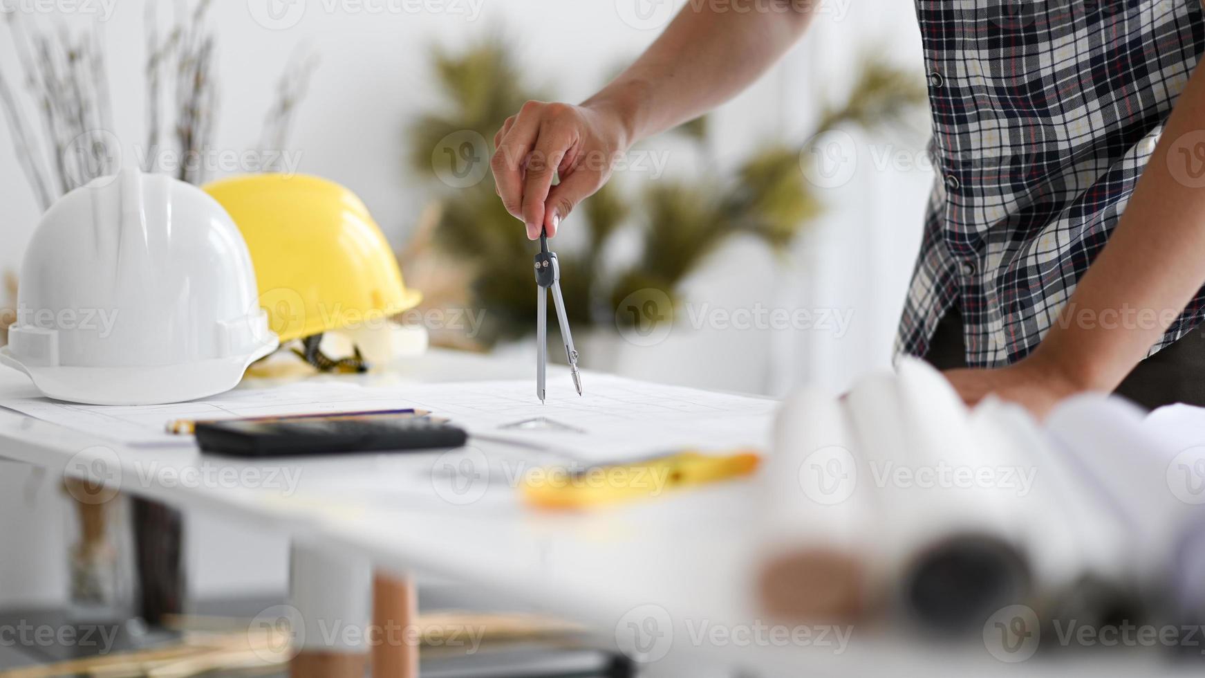 La mano del hombre está usando una rotonda para escribir un plano de la casa. foto