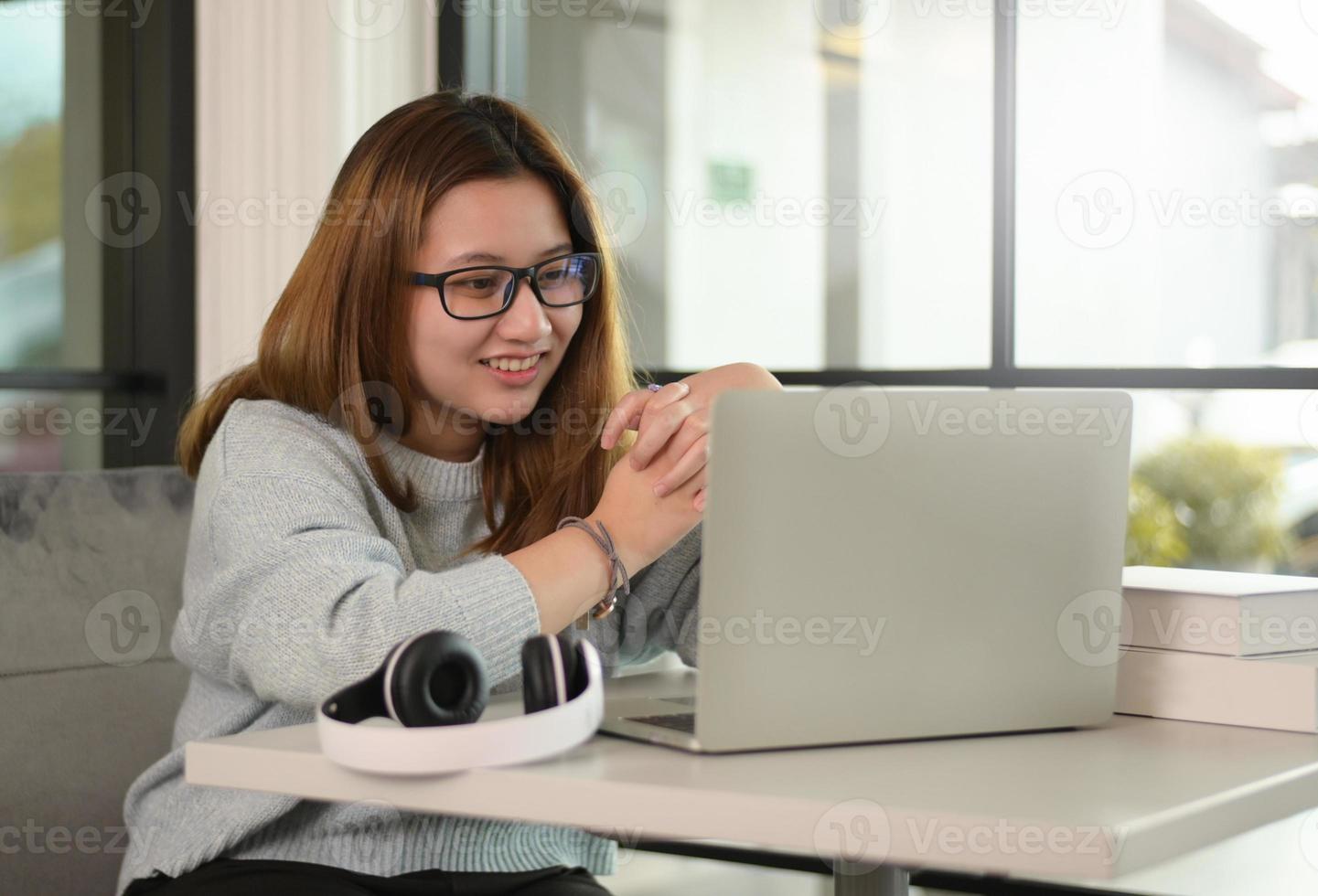 una adolescente con gafas con una computadora portátil y auriculares. foto