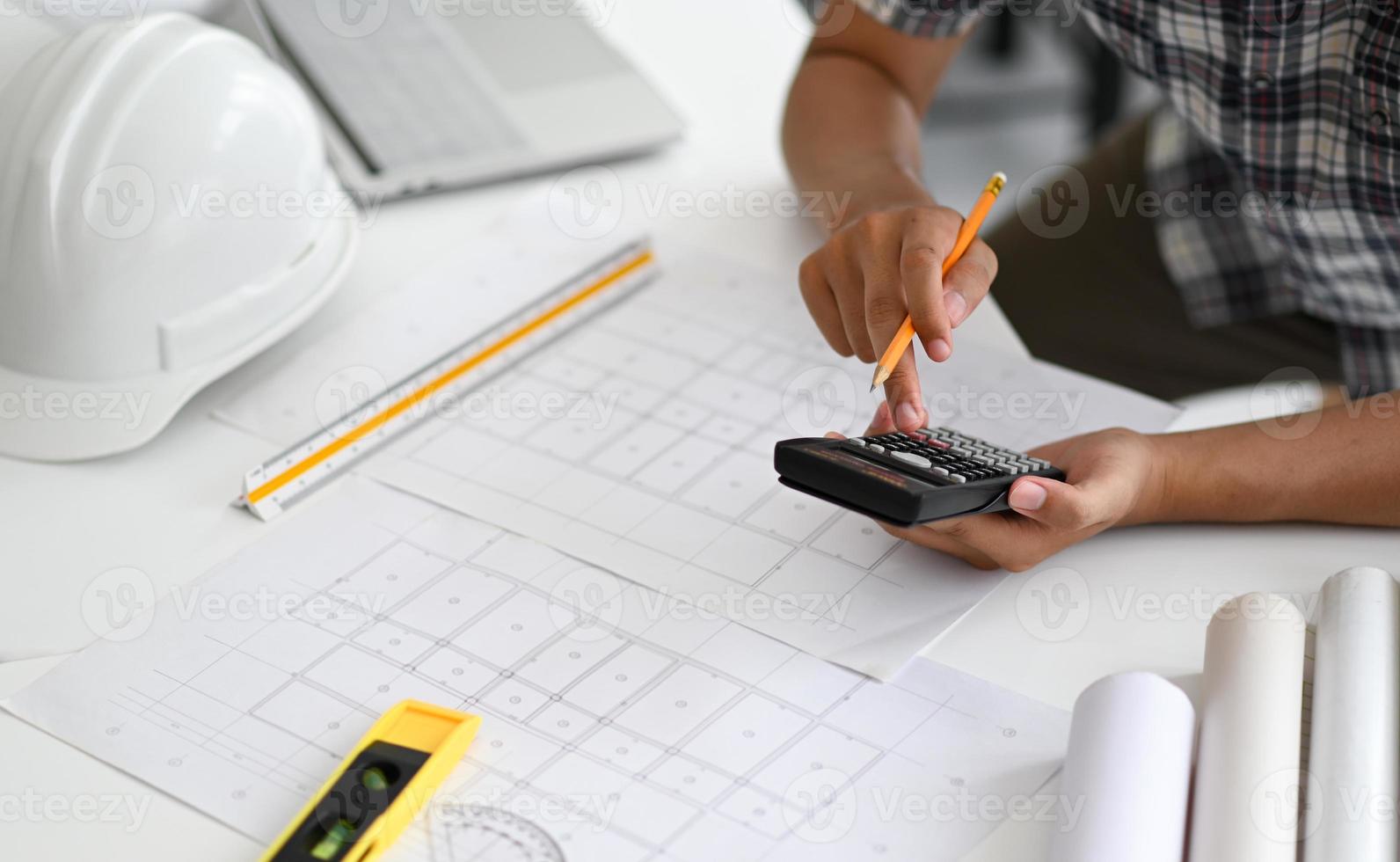 Architects are using a calculator to estimate the cost of house plans. photo