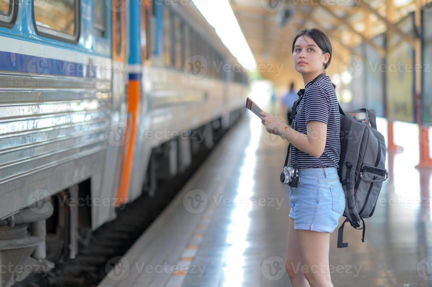 viajero internacional femenino que sostiene el mapa con la mochila esperando el tren. foto