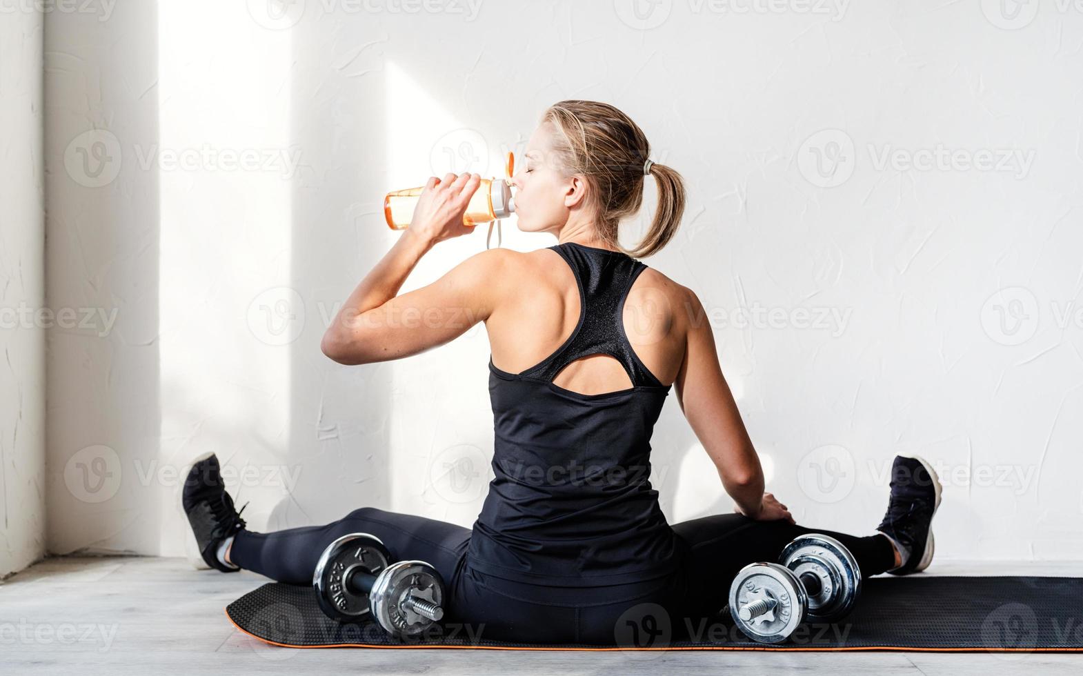 Mujer trabajando con pesas mostrando sus músculos de la espalda y los brazos foto