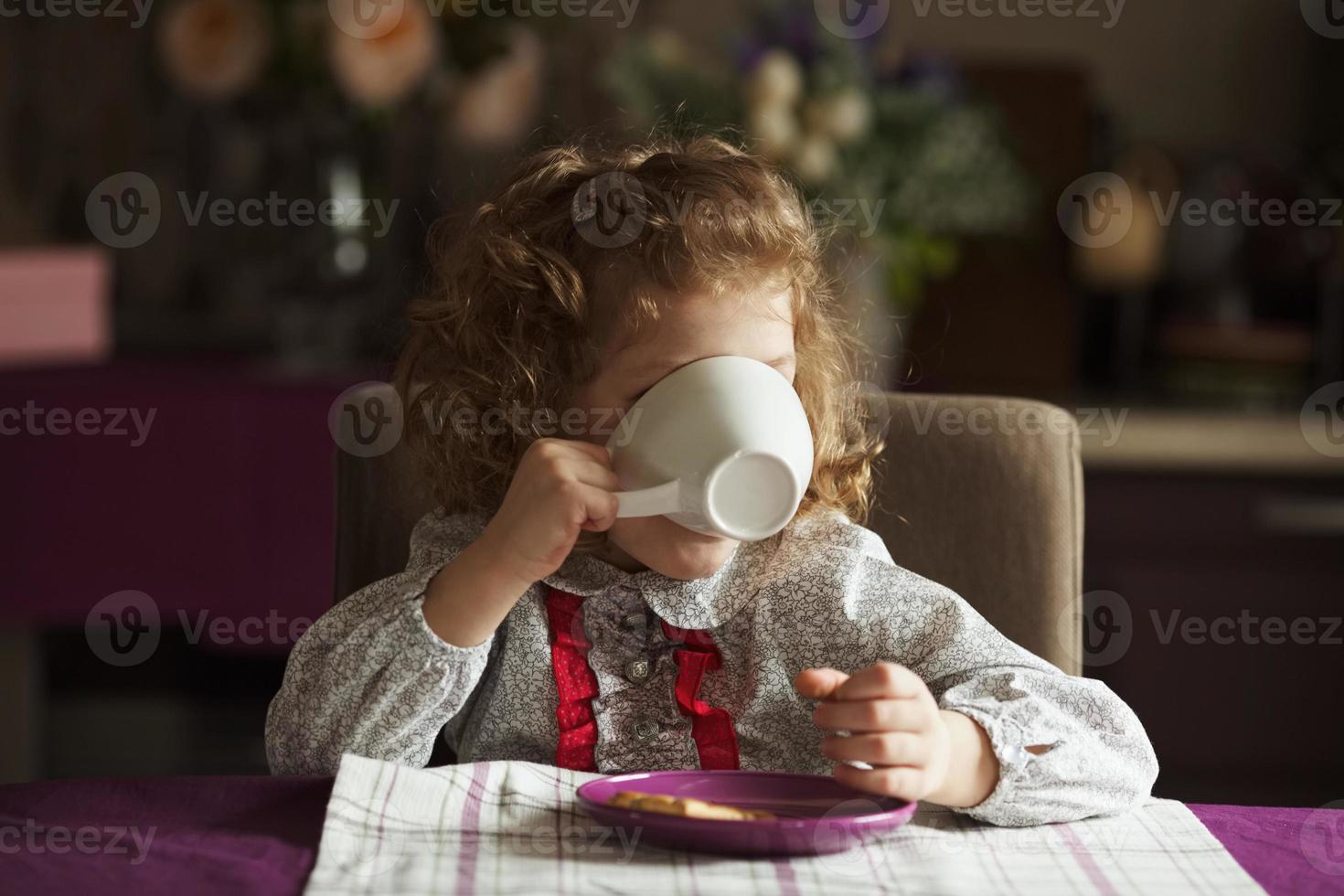 Little girl drinking from a big white cup photo