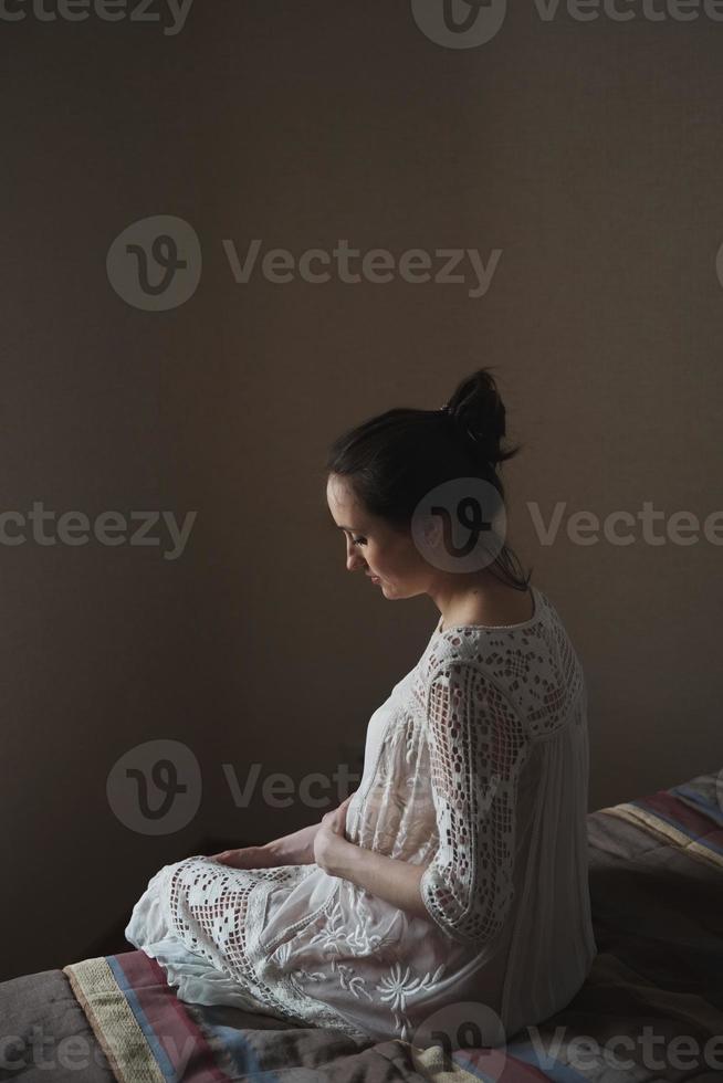 Pregnant woman sitting on a bed photo