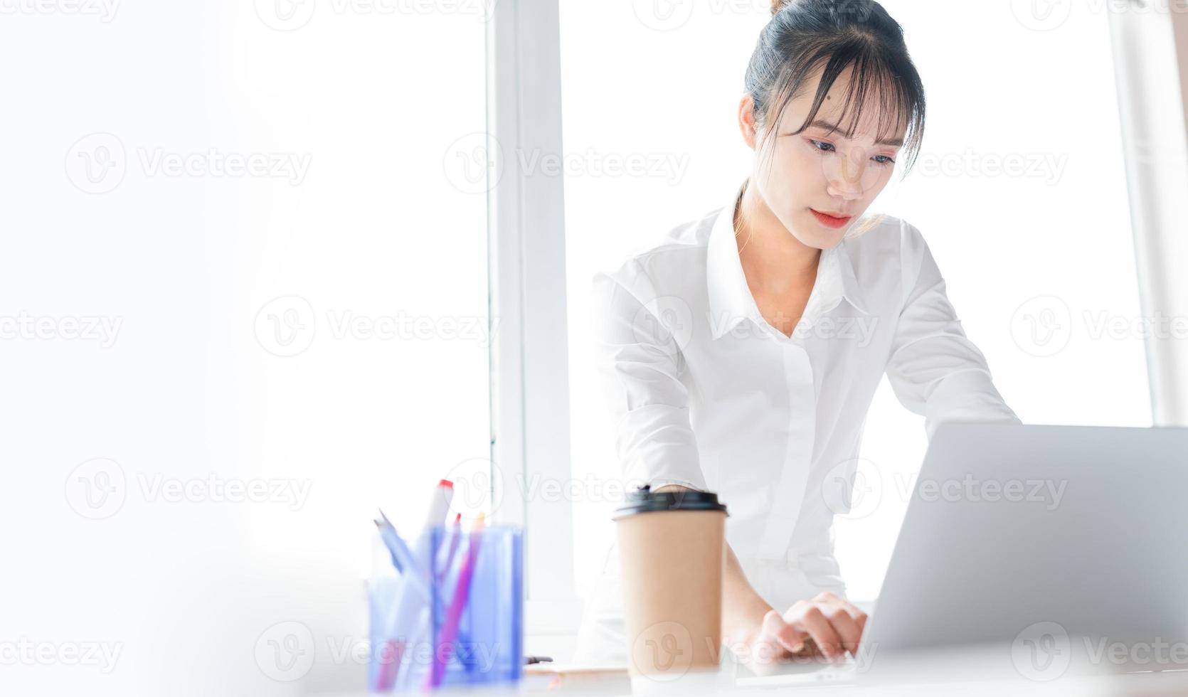 Portrait of young business woman standing and working together with laptop photo