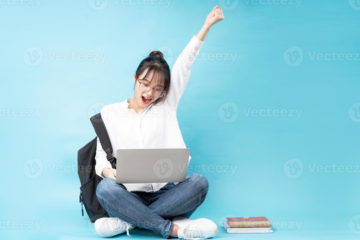 retrato, de, un, feliz, mujer joven, sentado, en, un, fondo azul foto