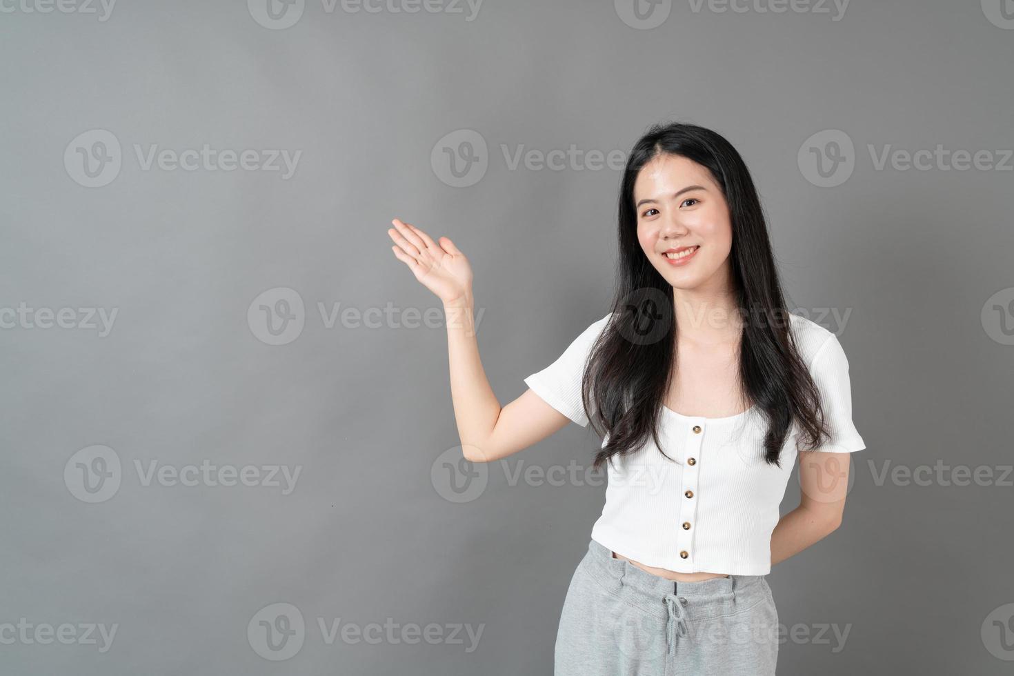 Mujer asiática con rostro sonriente y presentación de la mano en el lateral foto