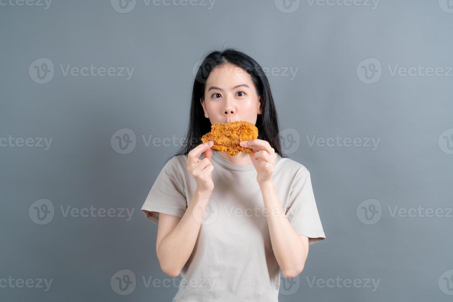 Joven mujer asiática con cara feliz y disfruta comiendo pollo frito foto