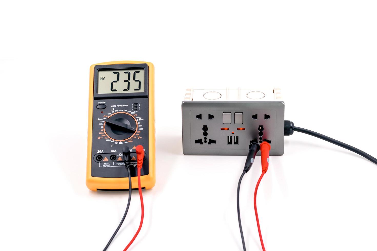 Using a digital meter to measure the voltage at a electric socket box on white background. photo