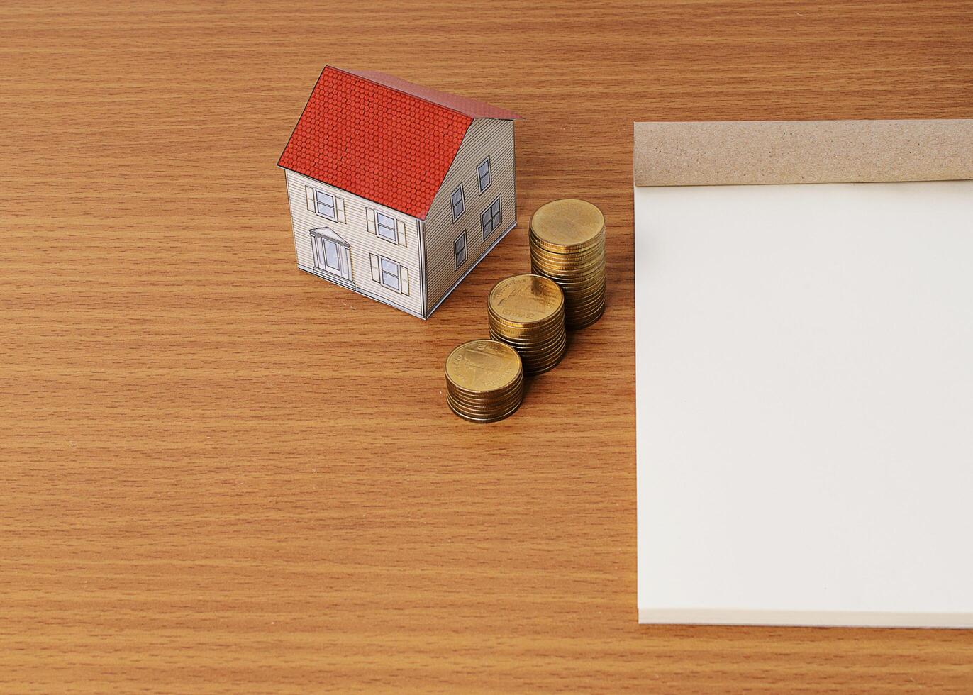 Mortgage loans concept with paper house with coins stack and notepad photo