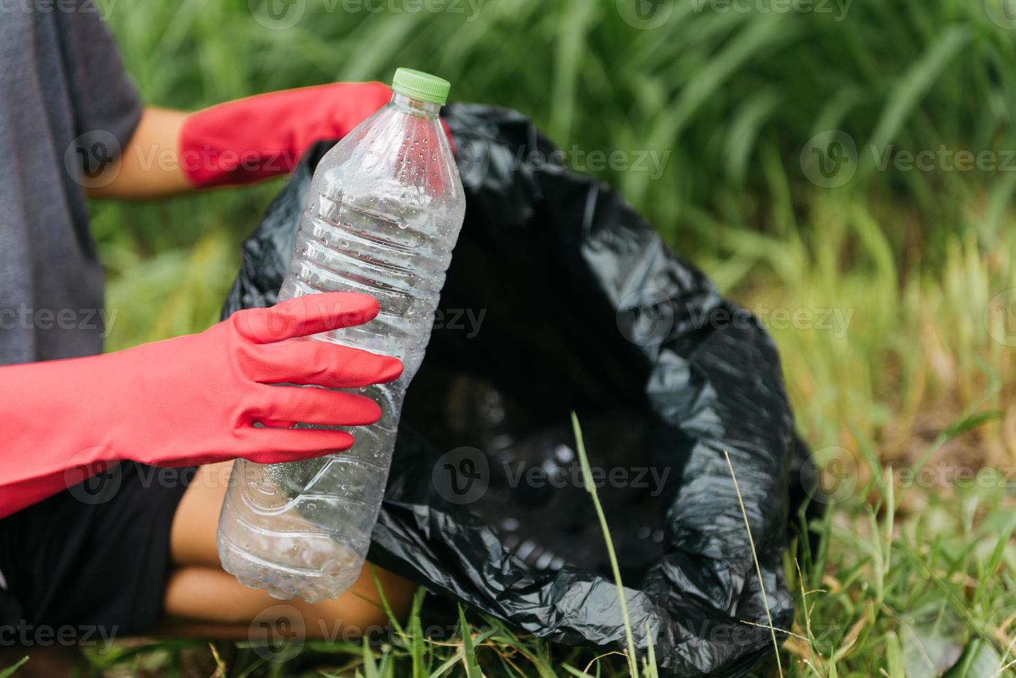 La mano del hombre del muchacho recoge la botella plástica en el bosque. concepto de medio ambiente. foto