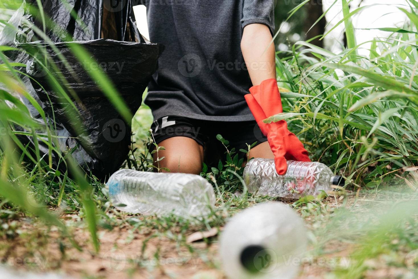 Boy man hand pick up plastic bottle in forest. Environment concept. photo