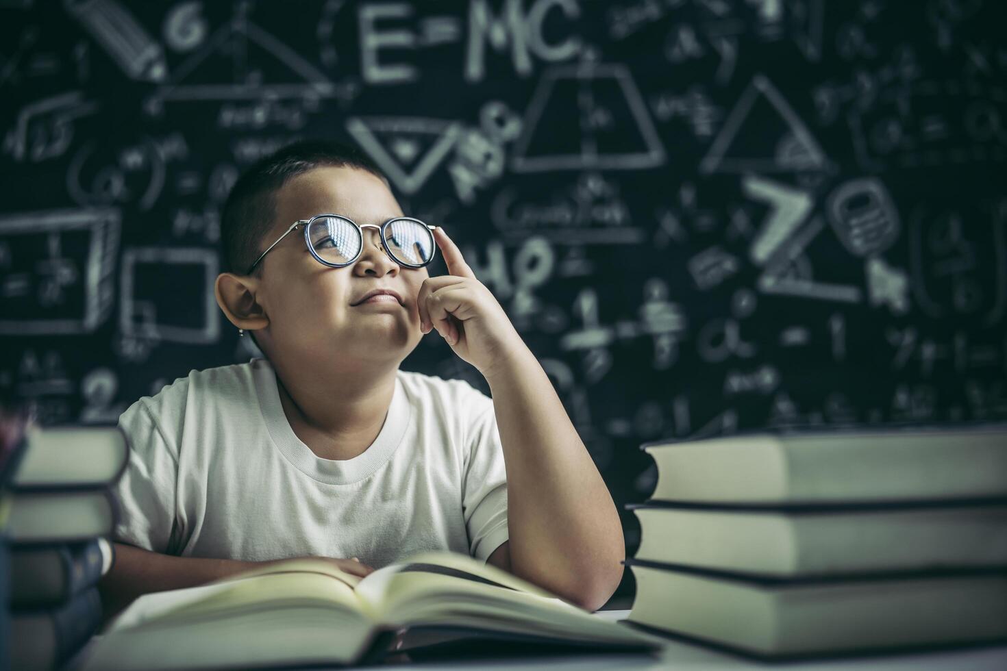 Los niños con gafas escriben libros y piensan en el aula. foto