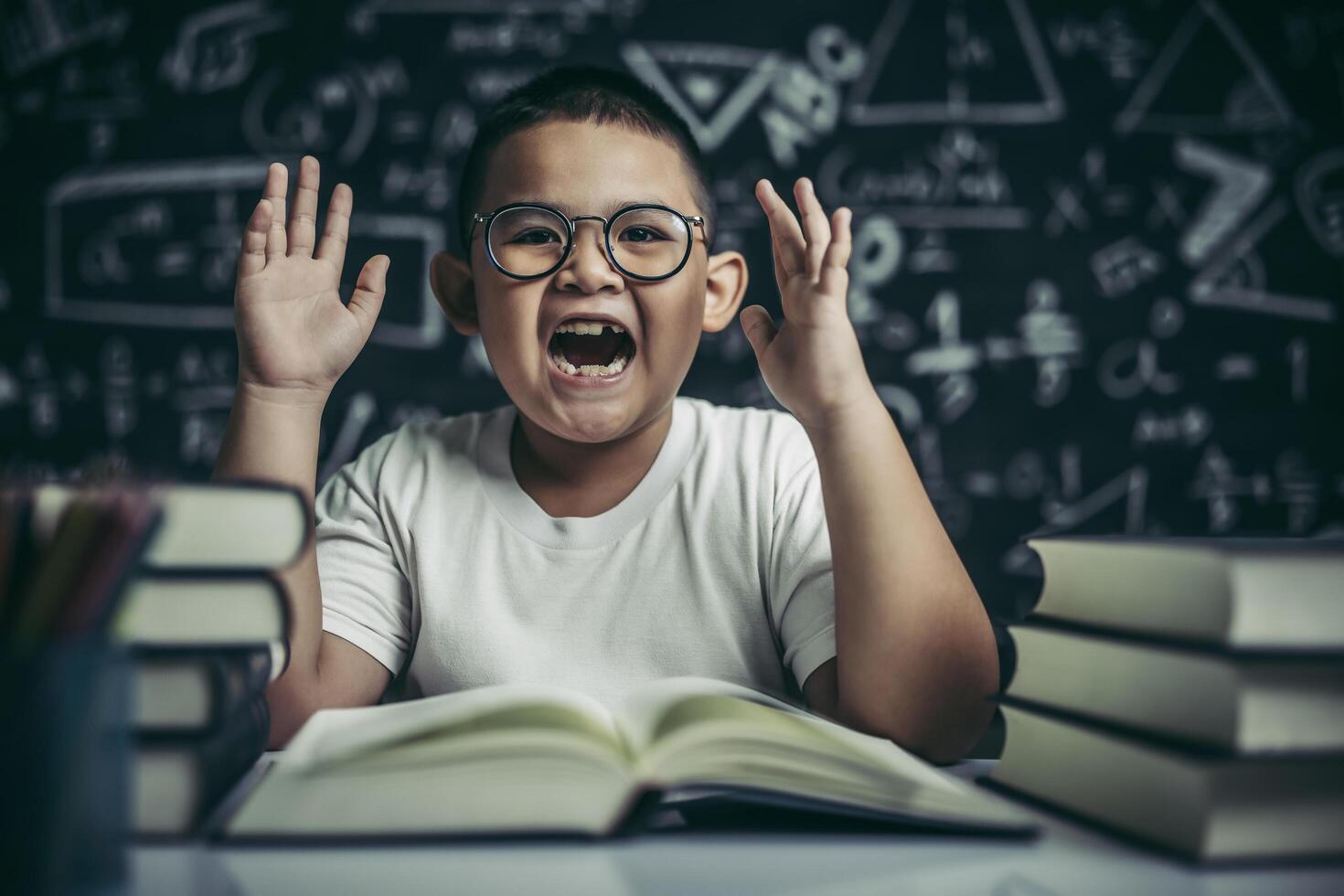 A boy with glasses sitting in the classroom reading photo