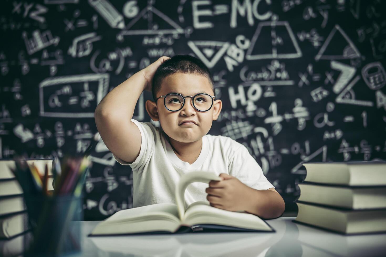 Los niños con gafas escriben libros y piensan en el aula. foto