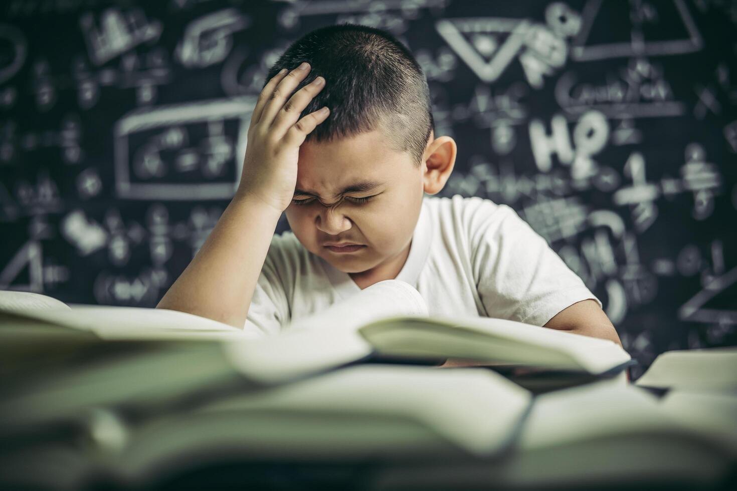 Boys with glasses write books and think in the classroom photo